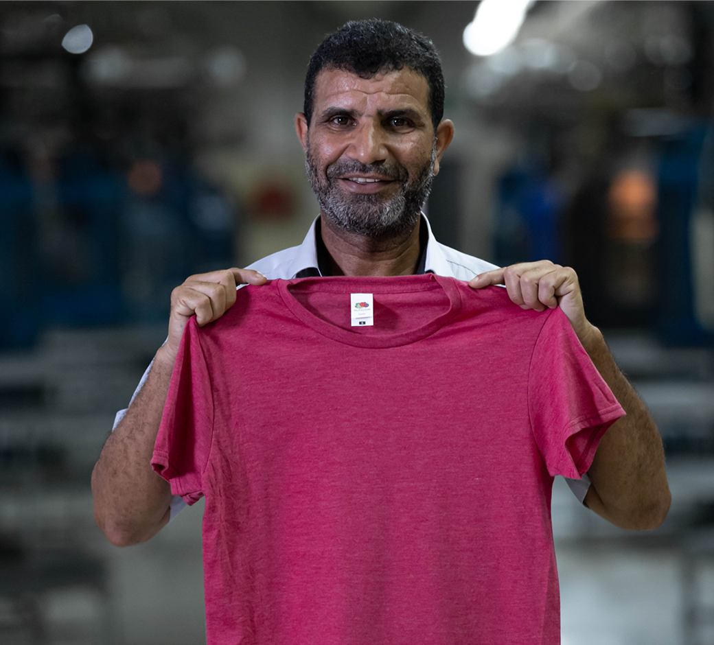 A man holding up a Burgundy Fruit of the Loom Iconic 195 T-shirt